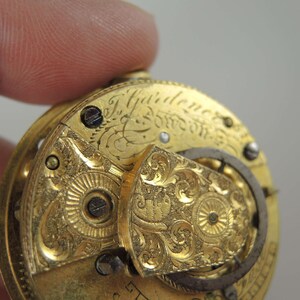 K&ouml;nnte beinhalten: Nahaufnahme einer goldenen Taschenuhr mit aufwendigen Gravuren und der Inschrift "J.  Yairden & Son London".