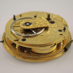 May include: A gold pocket watch movement with intricate engravings and a visible escapement mechanism.