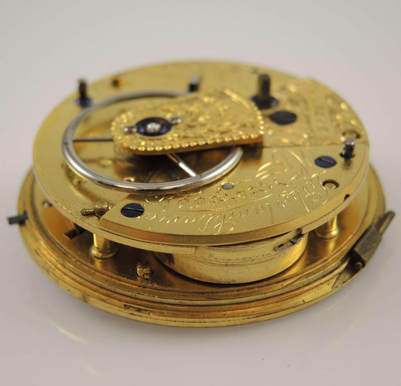 May include: A gold pocket watch movement with intricate engravings and a visible escapement mechanism.