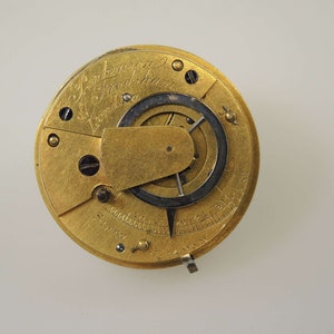 May include: A gold-toned pocket watch with the inscription "J. Parkinson & Son London" and a visible gear mechanism.