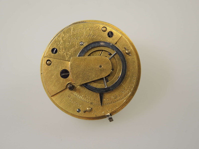 May include: A gold-toned pocket watch with the inscription "J. Parkinson & Son London" and a visible gear mechanism.