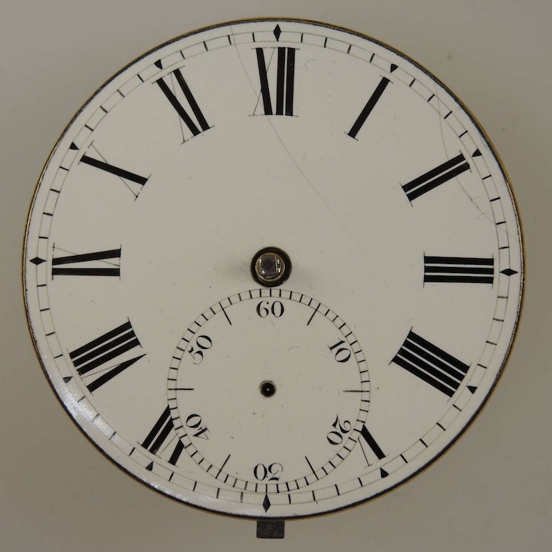 Puede incluir: Esfera de reloj blanca con marcadores de hora en n&uacute;meros romanos negros y marcadores de minutos negros. El reloj tiene un c&iacute;rculo conc&eacute;ntrico m&aacute;s peque&ntilde;o con marcadores de minutos negros.