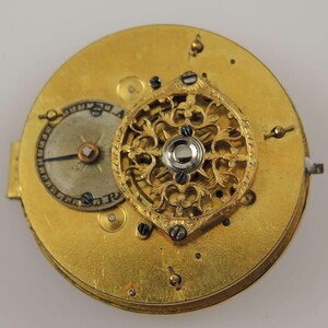 Puede incluir: Un reloj de bolsillo dorado con un dise&ntilde;o calado decorativo. La esfera del reloj es visible y tiene una sola aguja.