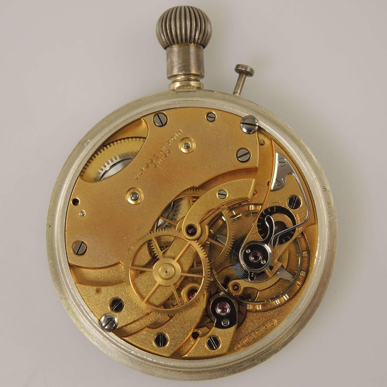 K&ouml;nnte beinhalten: Nahaufnahme des Uhrwerks einer antiken Taschenuhr. Die Uhr hat ein silberfarbenes Geh&auml;use und ein goldfarbenes Innenwerk mit komplizierten Zahnr&auml;dern, Schrauben und Juwelen. Oben sind eine silberne Krone und ein kleiner Knopf zu sehen. Wei&szlig;er Hintergrund.