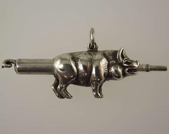 May include: A silver-toned pendant in the shape of a pig with a cylindrical extension. The pig is detailed with visible legs, ears, and snout. The pendant has a loop at the top for hanging.