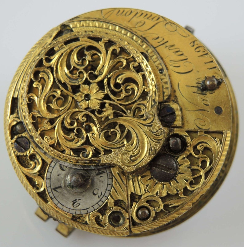 May include: A gold pocket watch with intricate floral engravings and the inscription "Thos. Clarke London 1728".