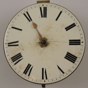 May include: A white clock face with black Roman numeral hour markers and black minute markers. The clock hands are gold colored.