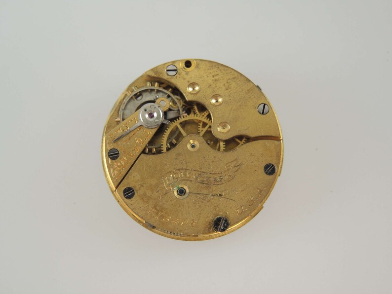 Puede incluir: Un movimiento de reloj de bolsillo de color dorado con engranajes expuestos y una inscripci&oacute;n 'Waltham'.