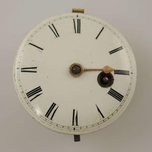 Könnte beinhalten: Ein Vintage-Zifferblatt mit weißem Hintergrund und schwarzen römischen Ziffern. Die Zeiger sind goldfarben und das Zifferblatt hat ein kreisförmiges Design. Das Zifferblatt ist ein klassisches Design, geeignet für antike oder Vintage-Projekte.