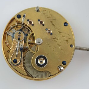 Puede incluir: Un movimiento de reloj de bolsillo de oro con engranajes intrincados y una aguja de acero azul. El reloj est&aacute; inscrito con "E. Howard & Co. Boston, 6798."