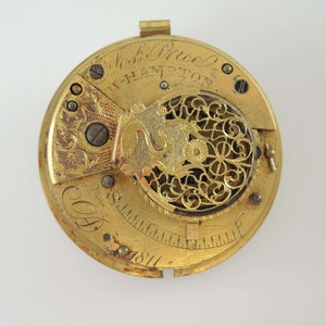 K&ouml;nnte beinhalten: Nahaufnahme eines Vintage-Taschenuhrwerks aus Gold. Der Uhrenmechanismus weist aufwendige Details auf, darunter eingravierte Muster, Zahnr&auml;der und die Inschrift "Nosh Price & W-Hampton". Das Datum "1811" ist ebenfalls sichtbar.