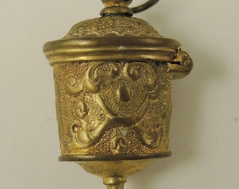 May include: A gold-colored metal thimble with an ornate design and a hinged lid. The thimble has a loop at the top for hanging.