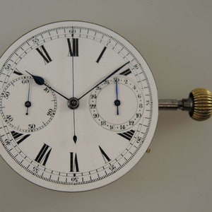 May include: A white chronograph pocket watch with black Roman numeral hour markers and black hands. The watch has two sub-dials, one for seconds and one for minutes. The watch is attached to a winding key.