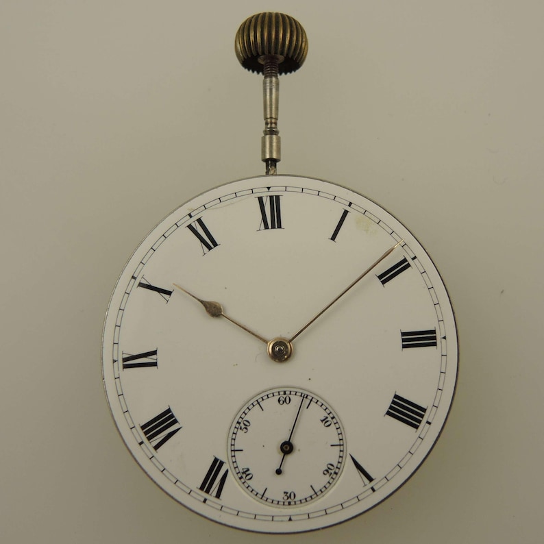 May include: Antique pocket watch with a white face, black Roman numerals, and delicate gold hands. The watch features a smaller subdial and a decorative winding stem. The watch is a classic timepiece.