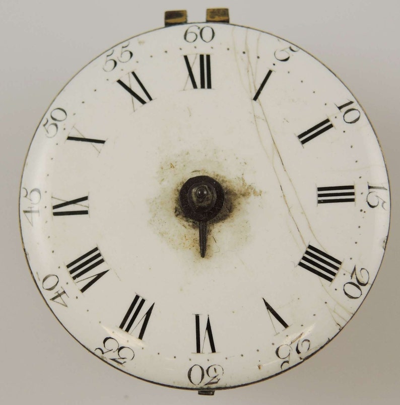 May include: White clock face with black Roman numeral hour markers and black minute markers. The clock face is cracked.