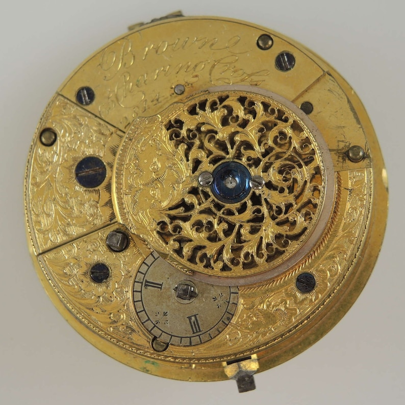 Puede incluir: Un reloj de bolsillo de oro con un intrincado dise&ntilde;o floral y la inscripci&oacute;n "J.B.  running a Watchmaker in  London".