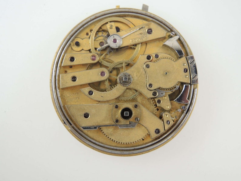 Op de afbeelding: Close-up van de ingewikkelde binnenkant van een gouden zakhorloge. Het uurwerk is zichtbaar en toont een complexe opstelling van tandwielen en veren.