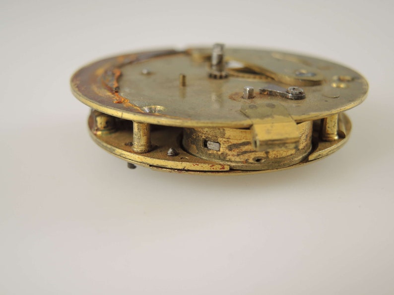 K&ouml;nnte beinhalten: Nahaufnahme eines Vintage-Uhrwerks, das seine inneren Mechanismen zeigt. Die Messingkomponenten weisen Alterserscheinungen und Rost auf, was die Geschichte der Uhr unterstreicht. Das Design umfasst Zahnr&auml;der, Hebel und andere kleine Teile.
