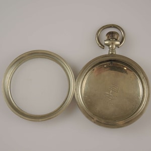 Può includere: Orologio da tasca in argento con un fondello incernierato. Il fondello è aperto e mostra l'iscrizione "Waltham Watch Company, Waltham, Mass. Pat'd. July 12, 1870."