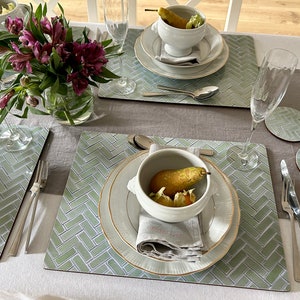 May include: A table setting with two place settings featuring white bowls with pears and a green and white patterned placemat. The placemats have a herringbone pattern.