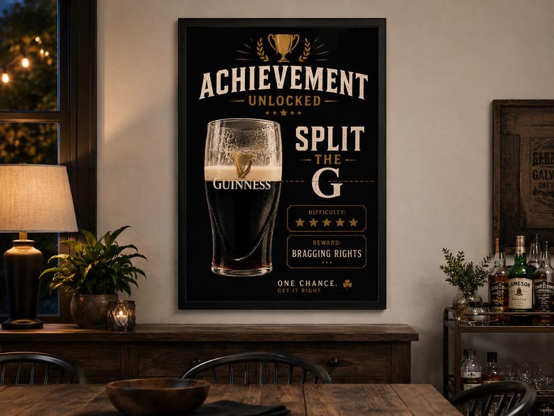 Puede incluir: P&oacute;ster de Guinness enmarcado en negro con el texto "ACHIEVEMENT UNLOCKED" y "SPLIT THE G". Una pinta de Guinness est&aacute; en el centro. El p&oacute;ster tambi&eacute;n incluye el texto "DIFFICULTY" y "REWARD BRAGGING RIGHTS".