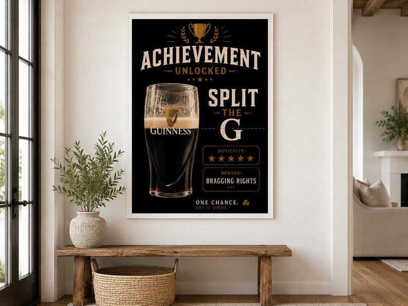 Puede incluir: Un p&oacute;ster negro enmarcado con el texto "ACHIEVEMENT UNLOCKED SPLIT THE G" y una pinta de Guinness. El p&oacute;ster incluye un gr&aacute;fico de trofeo y el logotipo de Guinness. La dificultad se califica con cinco estrellas, y la recompensa es "BRAGGING RIGHTS."
