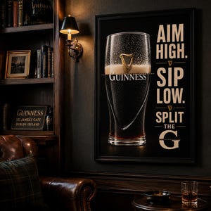 May include: A framed Guinness advertisement featuring a pint glass filled with dark stout and creamy foam. The text "AIM HIGH. SIP LOW. SPLIT THE G" is displayed on the right side. The image is set in a dark, wood-paneled room with a leather armchair.