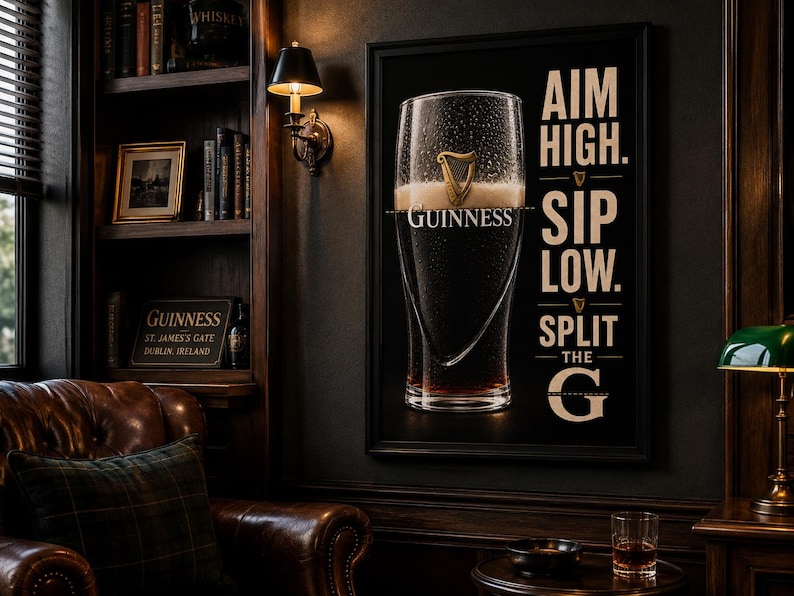 May include: A framed Guinness advertisement featuring a pint glass filled with dark stout and creamy foam. The text "AIM HIGH. SIP LOW. SPLIT THE G" is displayed on the right side. The image is set in a dark, wood-paneled room with a leather armchair.