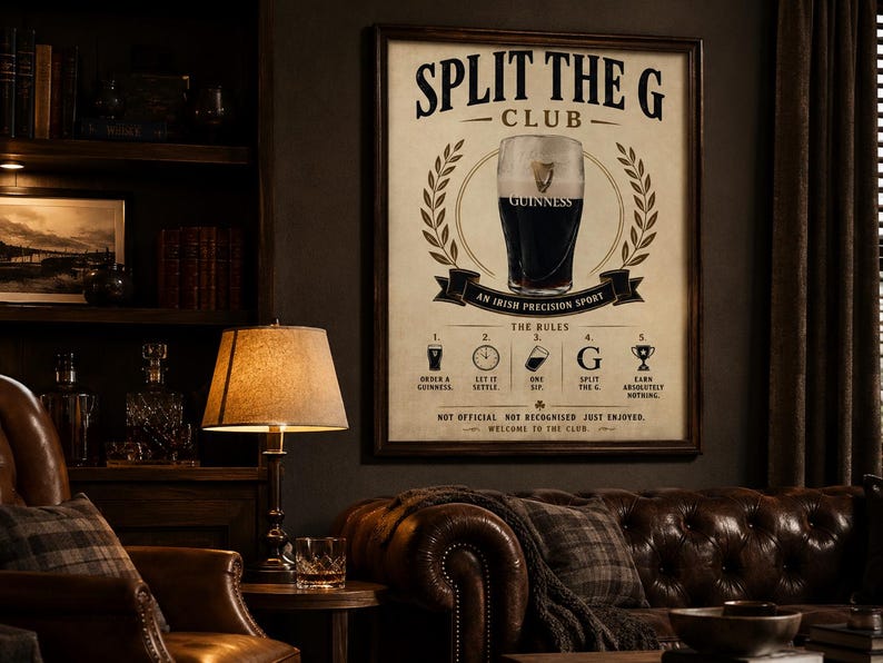May include: A framed poster with the text "SPLIT THE G CLUB" and an illustration of a pint of Guinness. The poster includes the words "AN IRISH PRECISION SPORT" and "THE RULES". The poster is displayed in a room with a leather sofa and a wooden bookshelf.