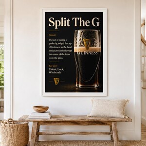 May include: A framed black and white print with the text "Split The G" and a definition of the act of drinking Guinness. The image features a pint of Guinness with the word "Guinness" visible. The print is displayed above a wooden bench.