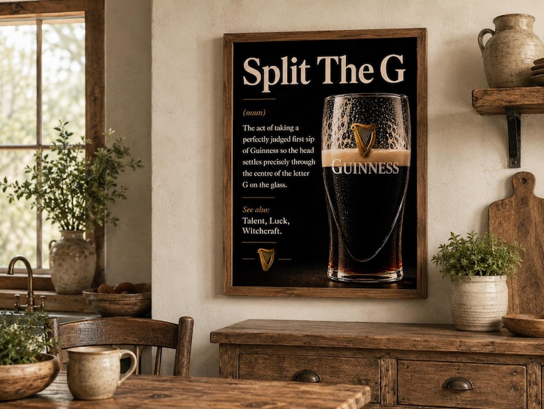 May include: A framed print with the text "Split The G" and a definition. The image features a pint of Guinness stout with the Guinness logo. The print is displayed in a rustic kitchen setting.
