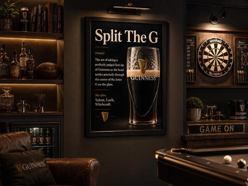 May include: A framed black sign with the text "Split The G" and a definition of the perfect Guinness sip. A pint of Guinness is in the center. The image is in a dark, cozy bar setting with a pool table and dartboard.