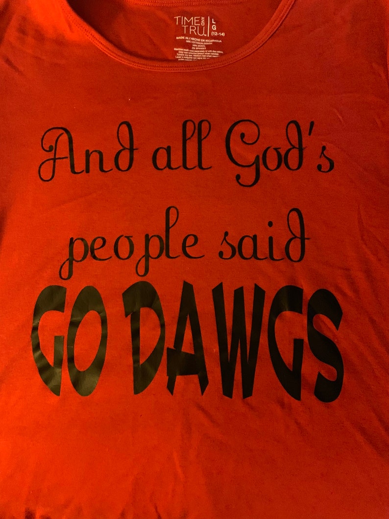 May include: Red t-shirt with the text "And all God's people said GO DAWGS" in black script. The shirt has a scoop neck and a tag that says "TIME AND TRU".