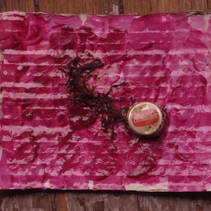 Puede incluir: Un papel rayado rosa y blanco con una mancha roja y un objeto marrón. Una tapa de botella roja y blanca con la palabra "Coca-Cola" impresa en ella está sobre el papel.