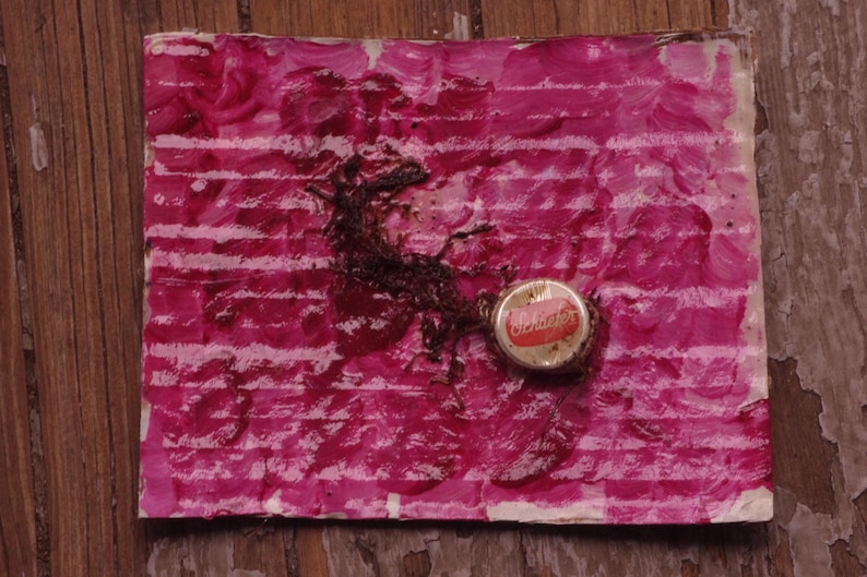 Może przedstawiać: Papier w r&oacute;żowo-białe paski z czerwoną plamą i brązowym przedmiotem. Czerwono-biała zakrętka butelki z nadrukiem "Coca-Cola" leży na papierze.