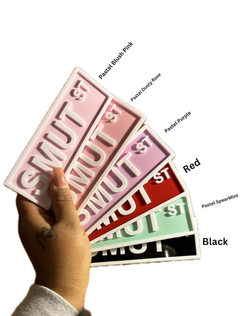 May include: A set of six "SMUT ST" signs in various colors, including pastel blush pink, dusty rose, purple, red, pastel spearmint, and black.