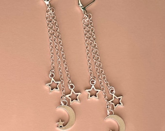 May include: A pair of silver dangle earrings with multiple chains and charms. Each earring features a crescent moon charm with a small star inside and three star charms.