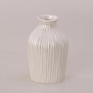 Może przedstawiać: Zestaw trzech ceramicznych kubków z nakrapianym, matowym wykończeniem. Kubki są w odcieniach kremu, jasnoszarym i ciemnoszarym. Każdy kubek ma prosty, minimalistyczny design i zaokrąglony uchwyt.