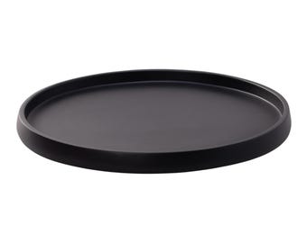 May include: A circular, matte black tray with a smooth, flat base and a slightly raised, rounded rim. The object features a uniform dark finish across its entire surface, presenting a simple, open design with no additional patterns or markings.
