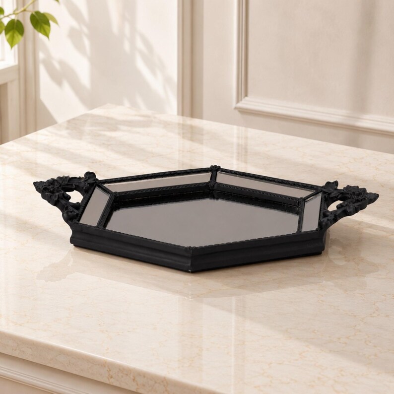 May include: A hexagonal tray featuring a central mirrored surface and a black frame. The tray includes two ornate, decorative handles on opposite sides, each detailed with intricate floral-like carvings and a matte black finish.