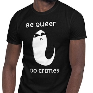 May include: Black t-shirt with the text "Be queer do crimes" and a white ghost graphic wearing sunglasses. The shirt is made of a soft material and is suitable for casual wear.