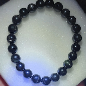 May include: A black beaded bracelet with a star-shaped pattern on each bead.