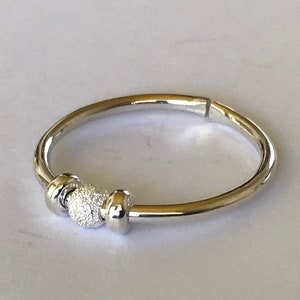 May include: A silver bangle bracelet with a textured ball charm.