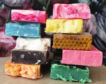 Può includere: Una pila di nove saponette artigianali colorate. Le saponette sono disposte a forma di piramide, con la saponetta più grande in basso e la più piccola in alto. Le saponette sono fatte con ingredienti naturali e hanno una varietà di profumi e colori.