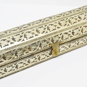 May include: A silver and brown decorative box with intricate floral patterns and a brass lock.