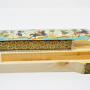 Puede incluir: Una caja de madera con una tapa con bisagras. La tapa est&aacute; decorada con una escena colorida de personas montando a caballo. La caja est&aacute; hecha de madera y tiene un patr&oacute;n decorativo en los lados.