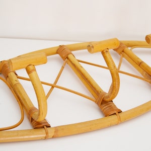 May include: A wall-mounted bamboo coat rack with three hooks. The rack is made of natural bamboo and has a light brown color.