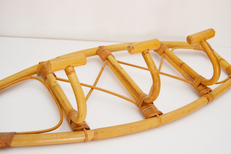 May include: A wall-mounted bamboo coat rack with three hooks. The rack is made of natural bamboo and has a light brown color.