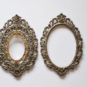 May include: Two ornate oval picture frames with a silver finish. The frame on the left has an inner gold frame.