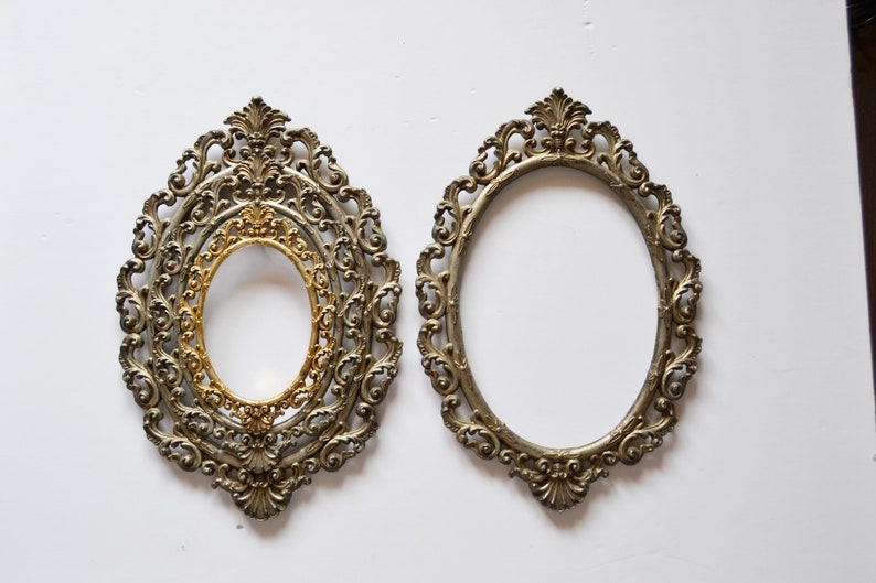 May include: Two ornate oval picture frames with a silver finish. The frame on the left has an inner gold frame.